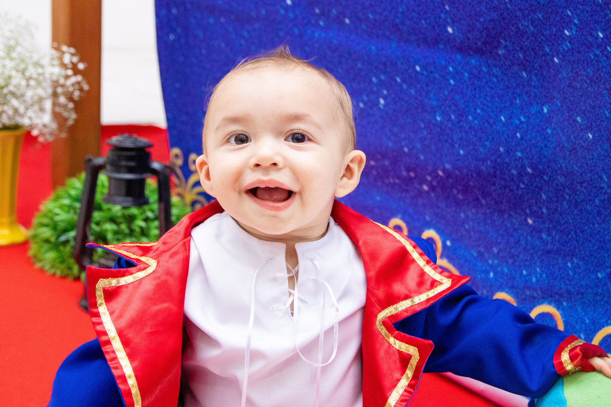 Aniversariante fantasiado de pequeno príncipe e sorrindo para a foto