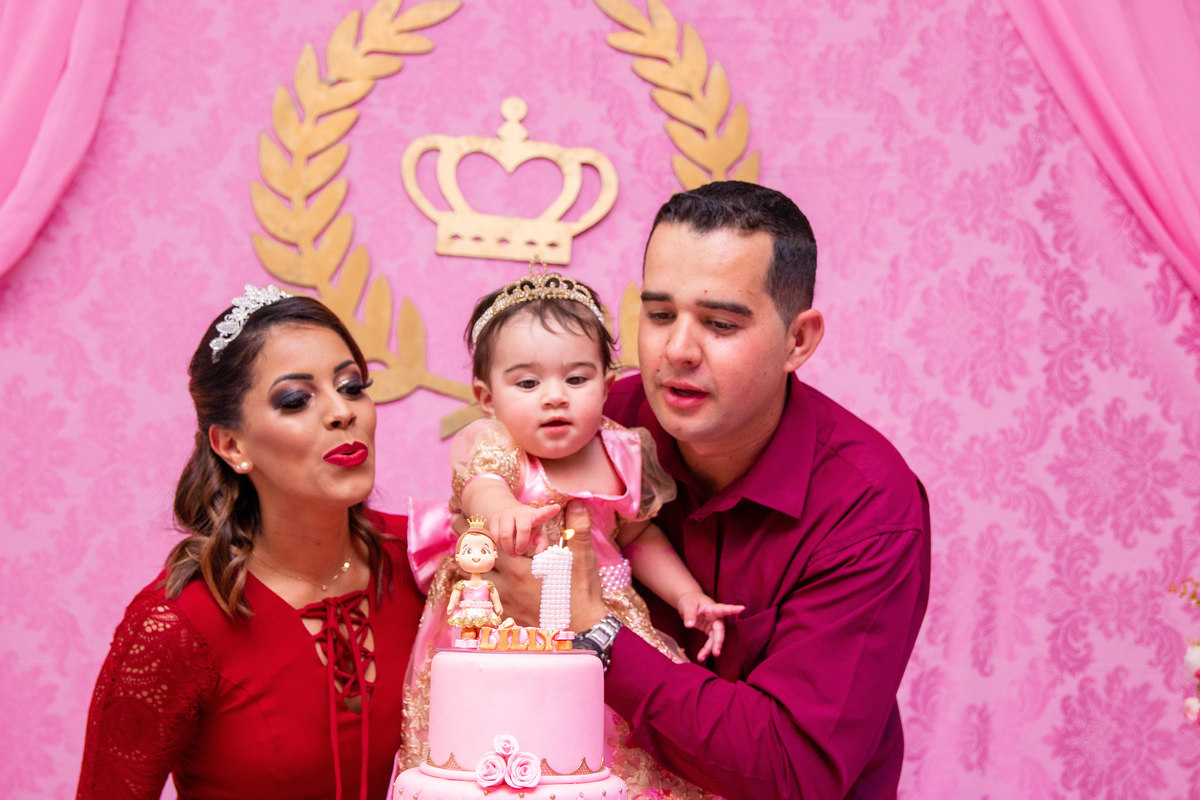 Aniversariante e seus pais assoprando a velinha em seu aniversário