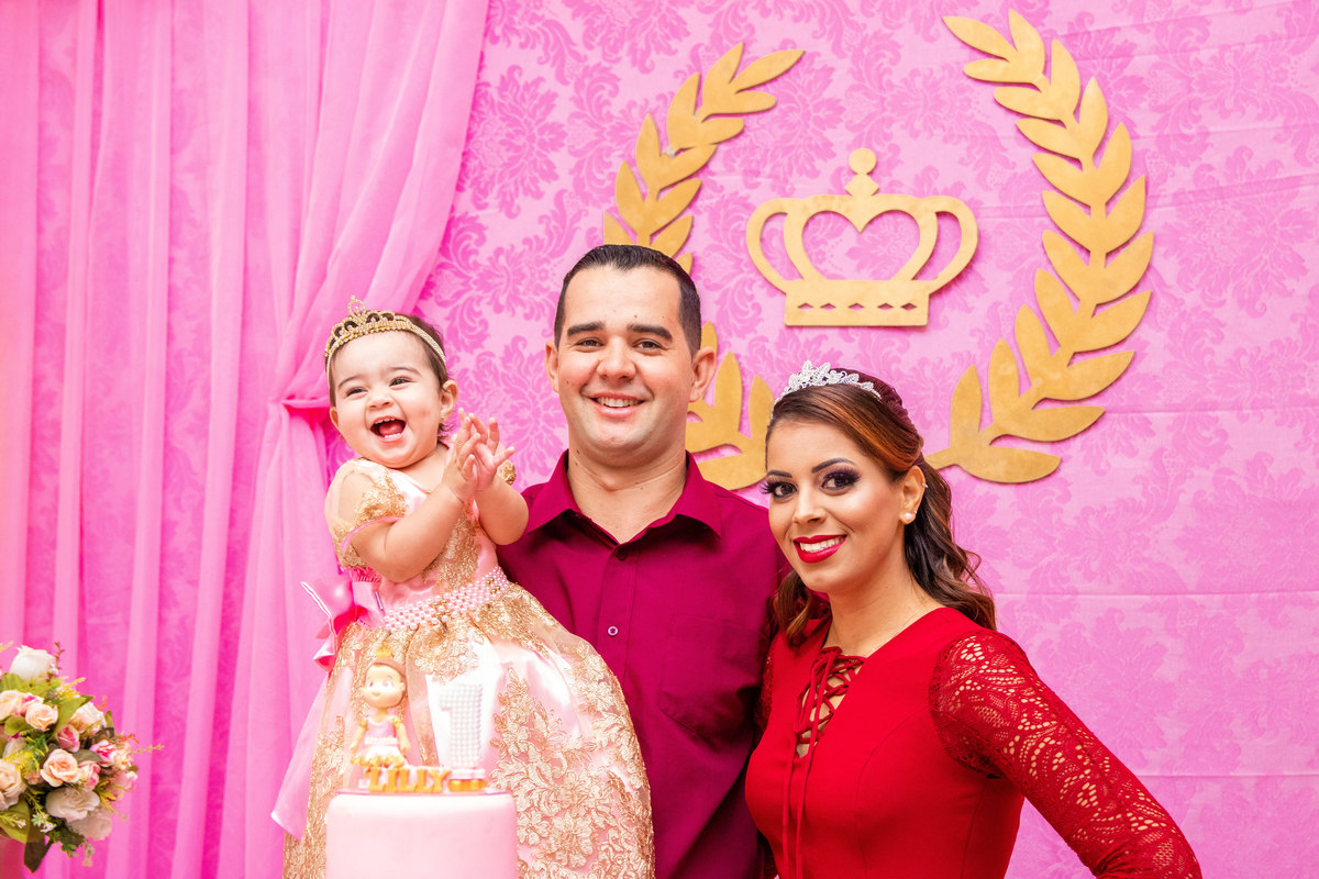 Pais e aniversariante sorrindo na mesa do bolo