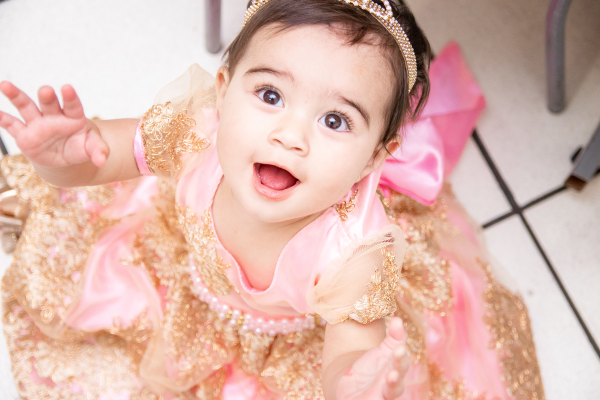 nenê de 1 ano vestida de princesa sorrindo em sua festa