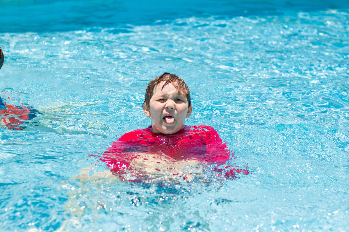 menino fazendo careta na piscina