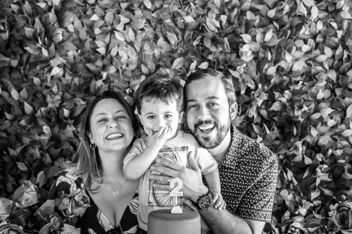 Pais e aniversariante rindo na mesa do bolo