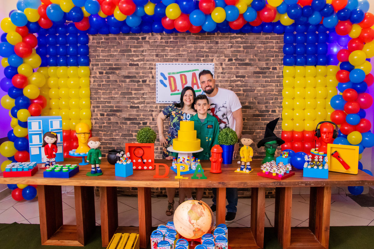 Aniversariante e seus pais na mesa do bolo