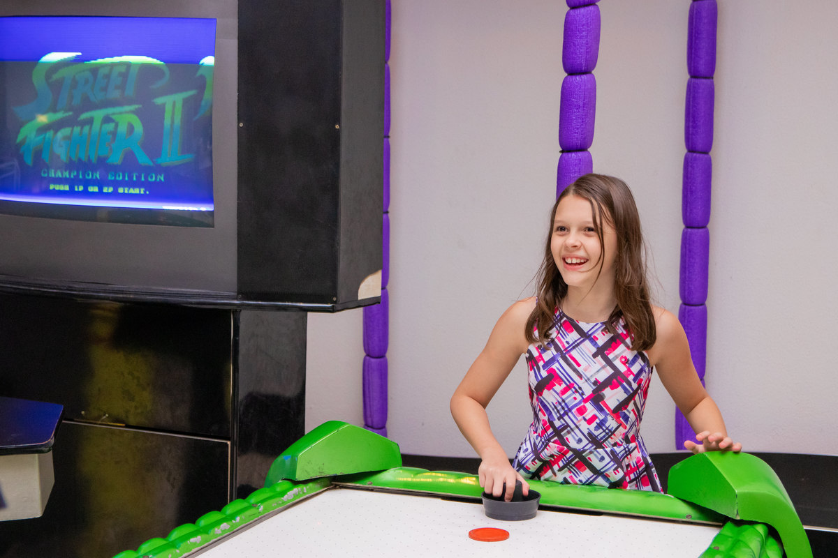 menina feliz jogando air hockey