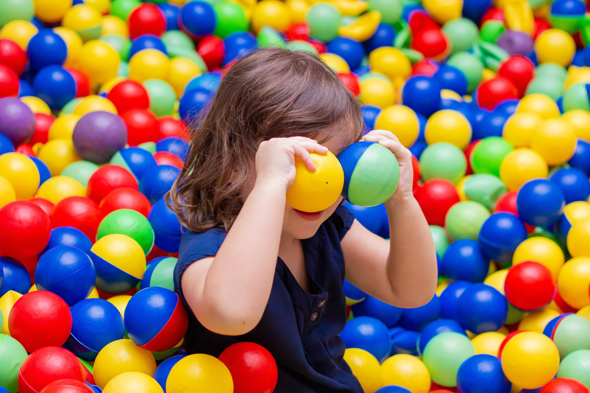Menina brincando com as bolinhas na piscina de bolinha
