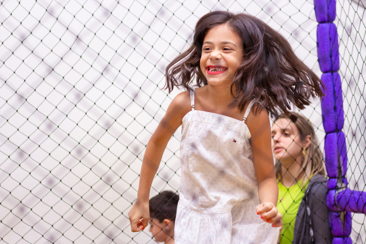 Menina feliz pulando na cama elástica