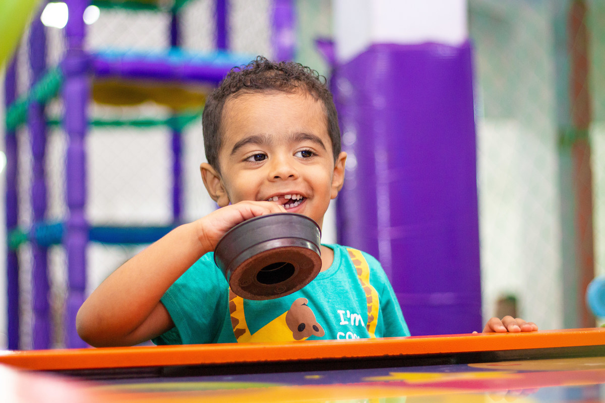 Menino feliz brincando no air hockey