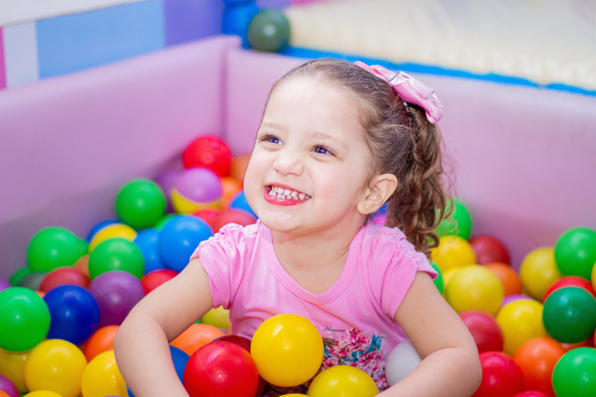 Menina sorridente na piscina de bolinhas no aniversário