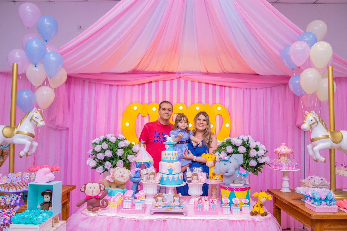 Aniversariante e seus pais na mesa do bolo