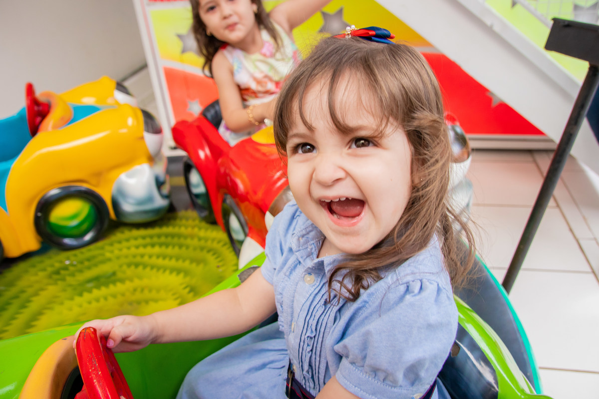 Aniversariante brincando de dirigir e sorrindo para a foto
