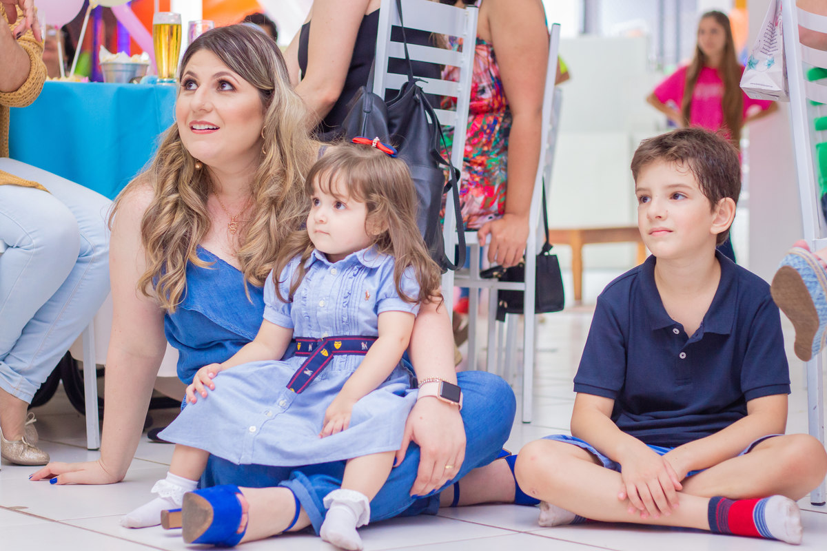 Aniversariante e convidados olhando a apresentação do perna de pau e malabarista 