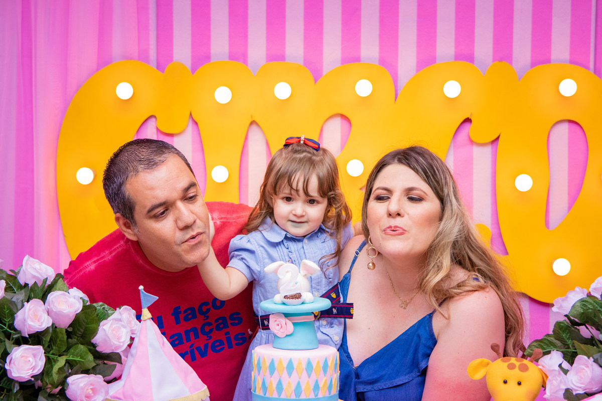 Aniversariante e seus pais assoprando as velinhas