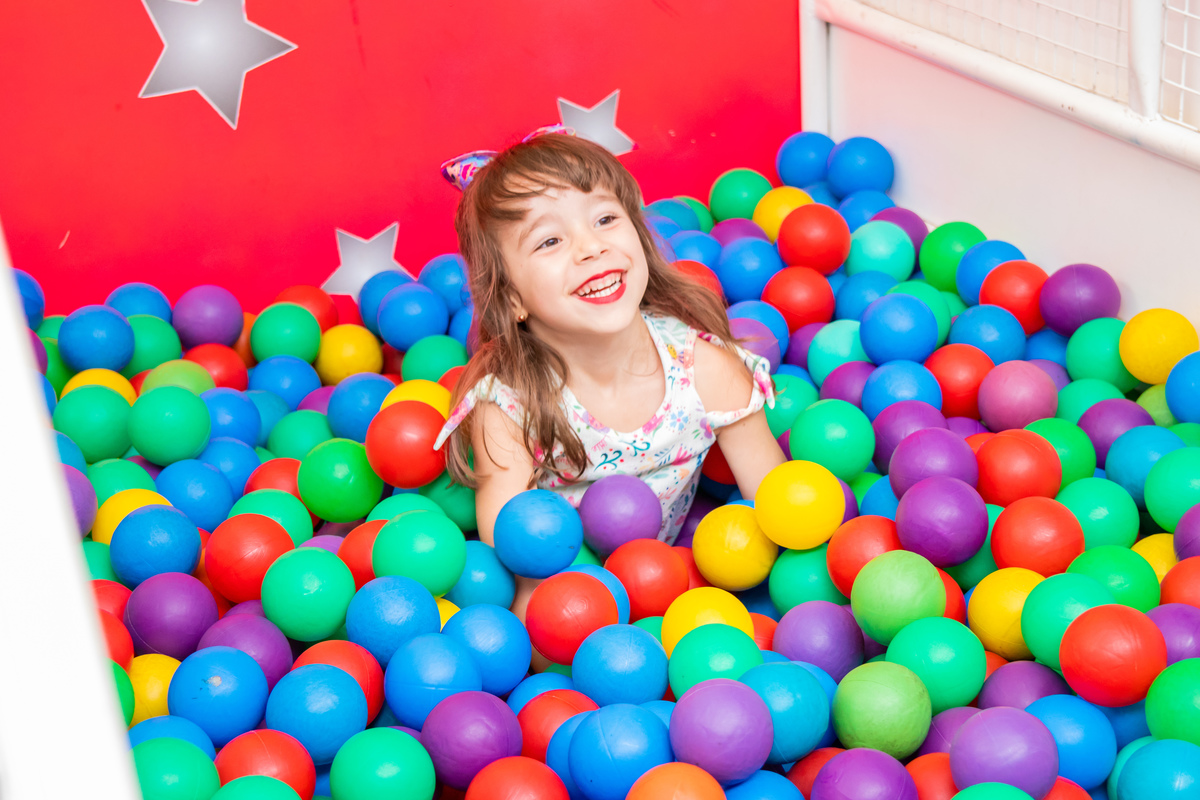 Menina sorrindo na piscina de bolinhas