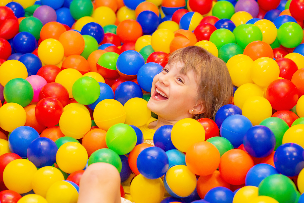 Garotinha rindo na piscina de bolinhas em festa infantil 