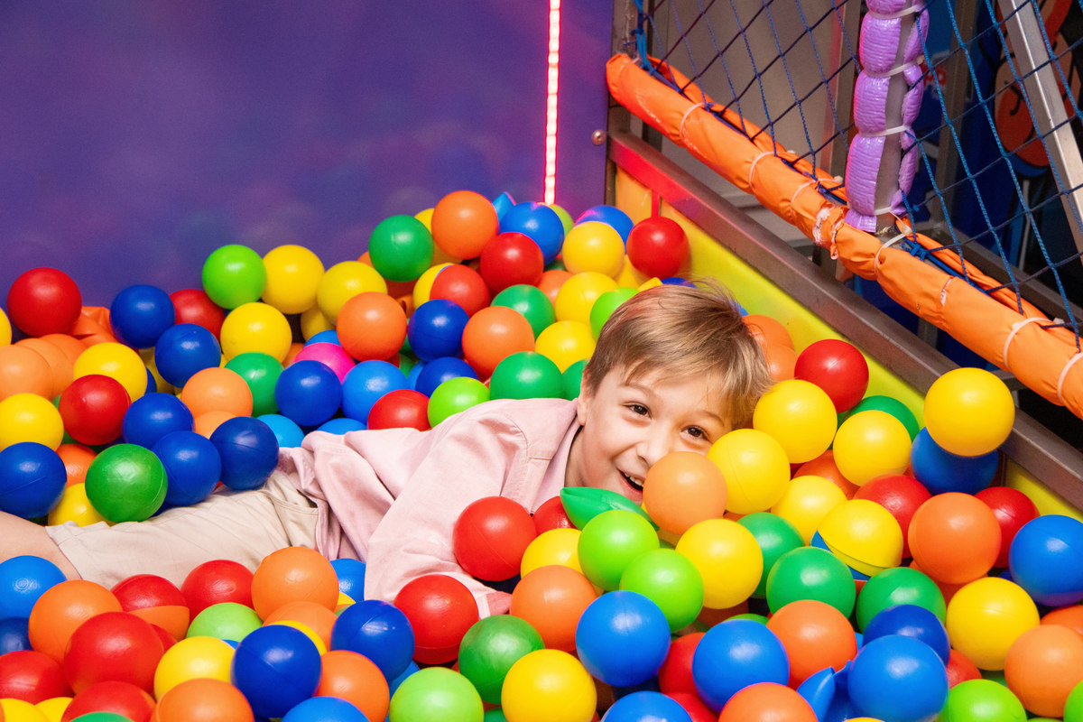 menino se escondendo na piscina de bolinha