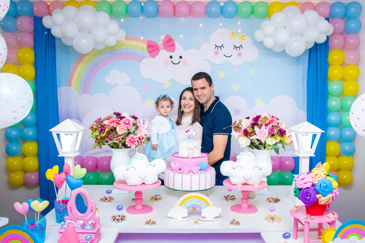 Aniversariante e seus pais na mesa do bolo