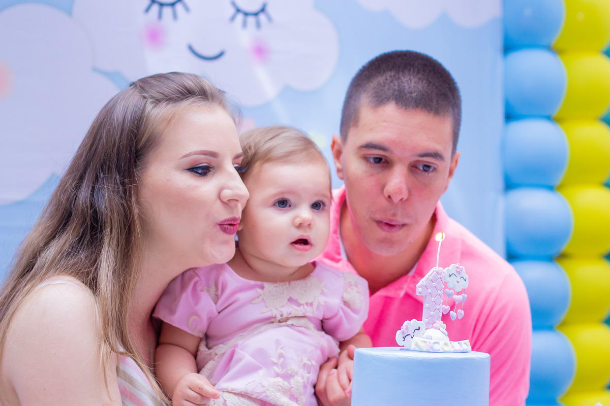 Aniversariante e seus pais assoprando a velinha