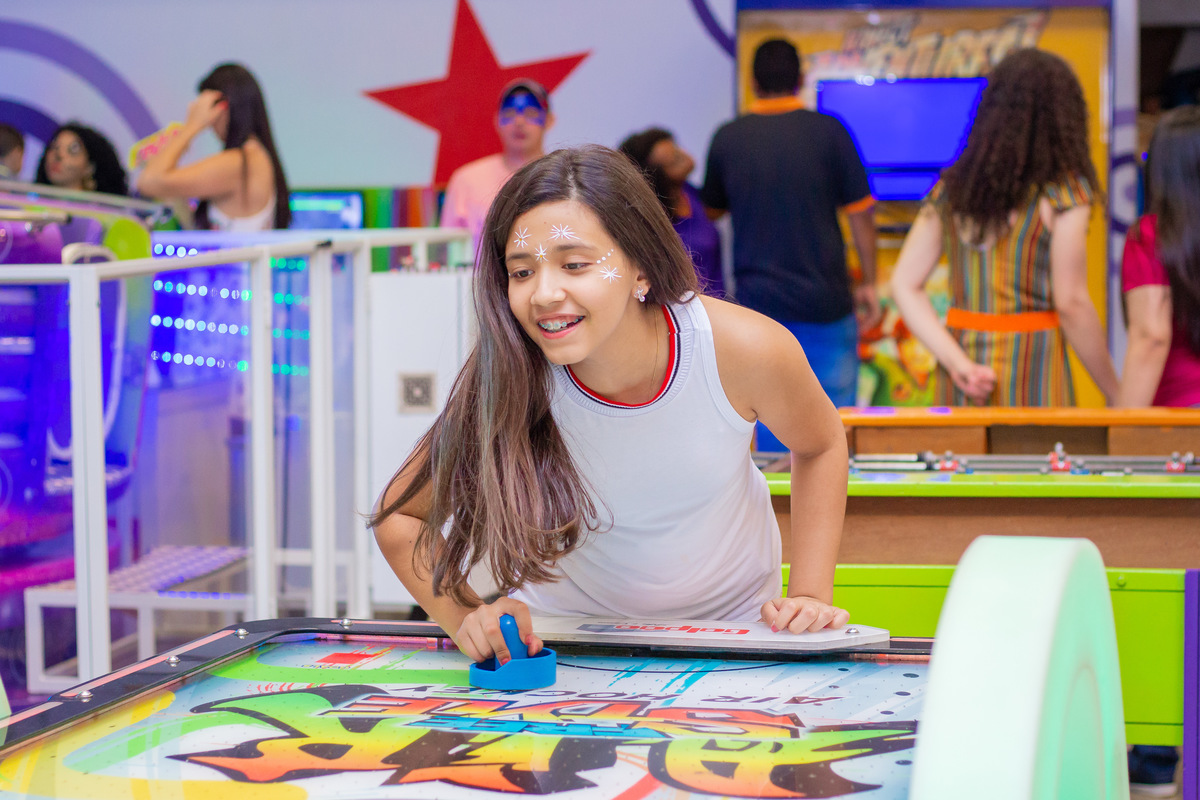 adolescente jogando air hockey em aniversário 