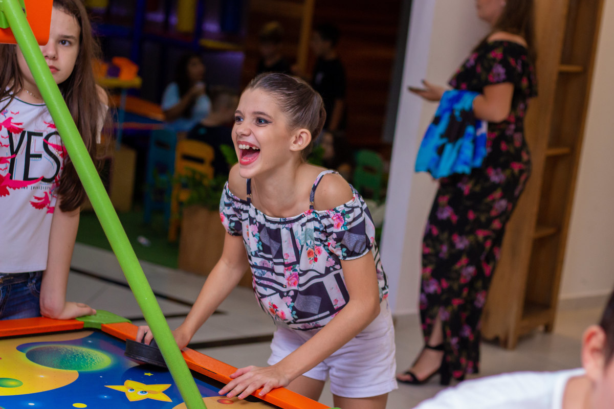 Buffet Zappteen Bauru, menina sorridente brincando no air hockey