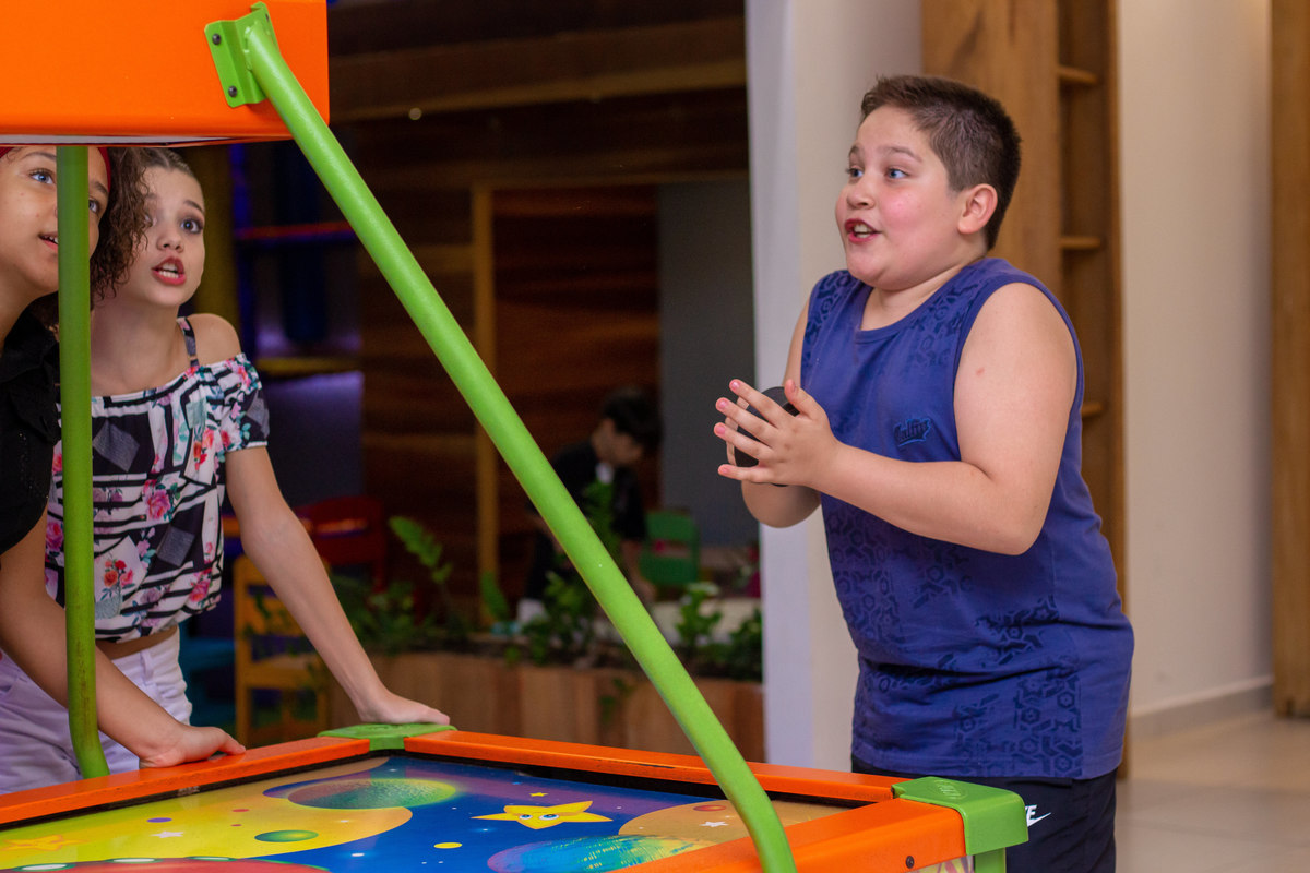 Buffet Zappteen Bauru, aniversariante fazendo caretas ao brincar no air hockey
