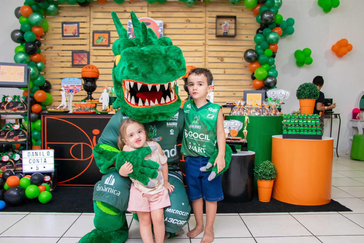 aniversariante e sua irmã tirando foto com mascote do bauru basket