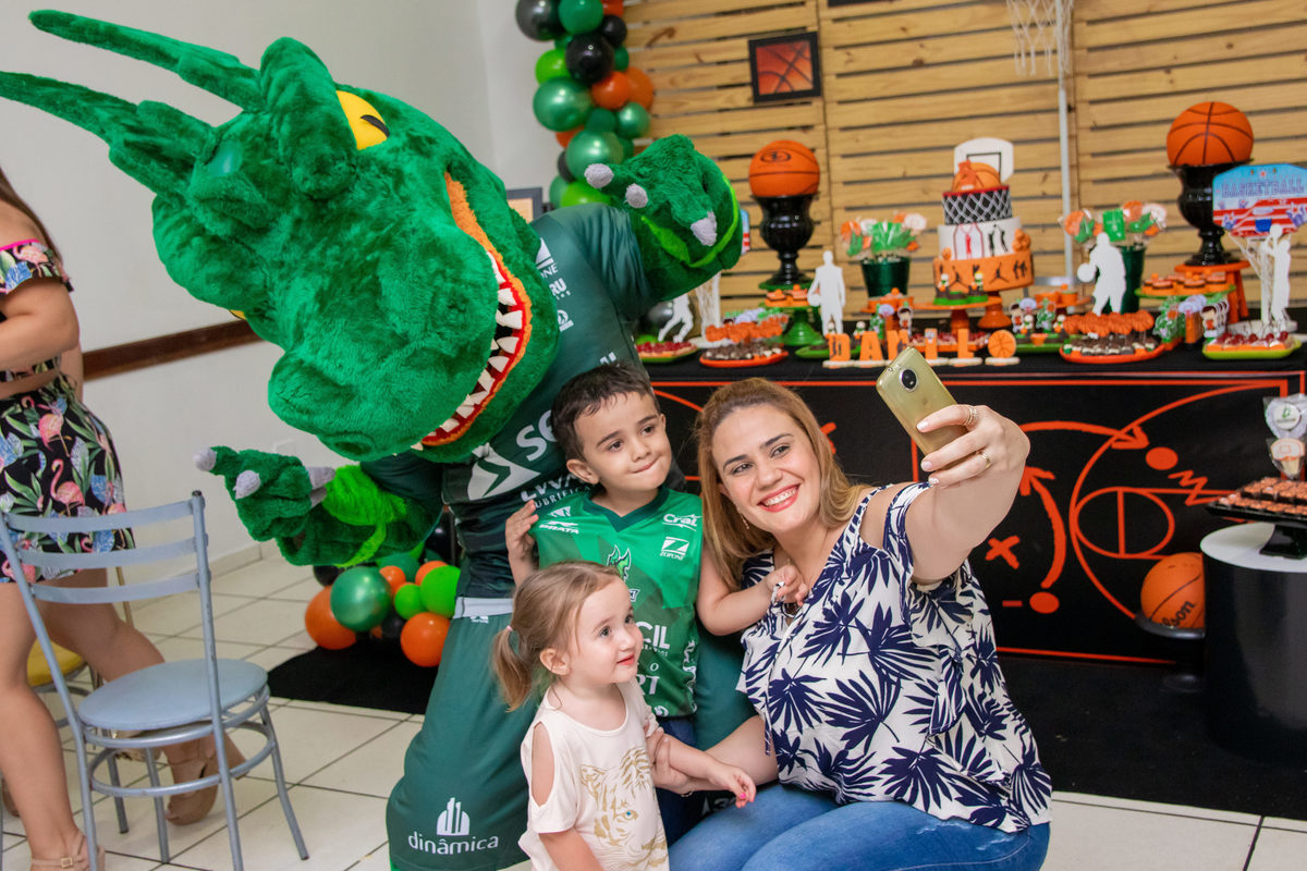 Aniversariante e sua família tirando foto com mascote do bauru basket