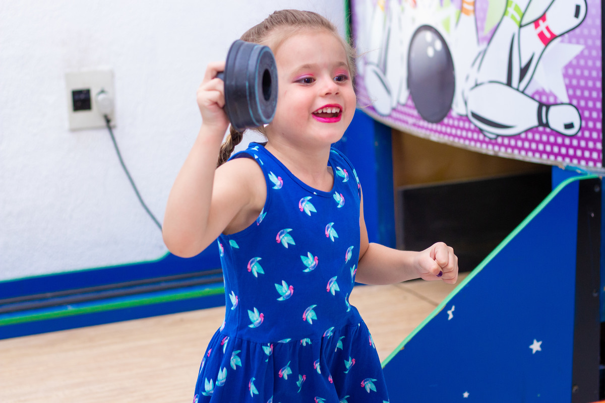 menina de vestido azul rindo no air hockey