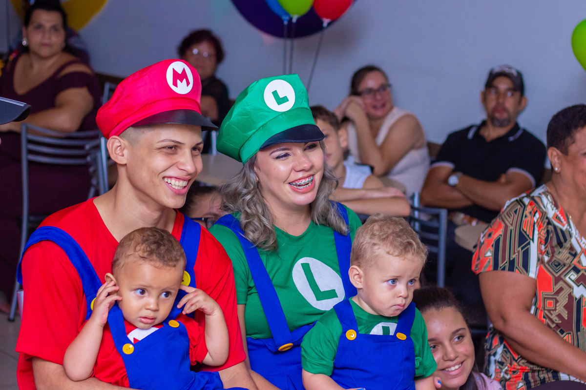 Família sorrindo ao ver a retrospectiva animada, família fantasiada Mario Bros