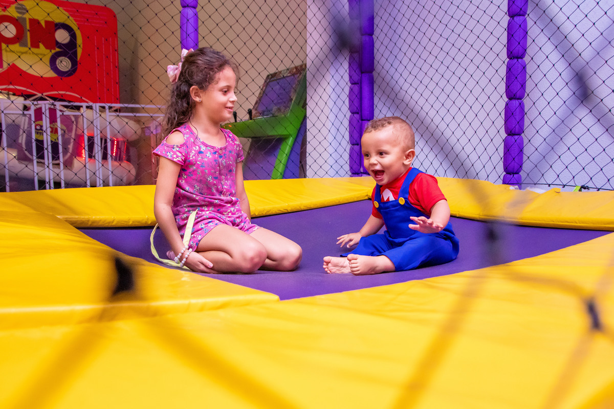 Aniversariante e amiga na cama elástica, aniversariante rindo em seu aniversário