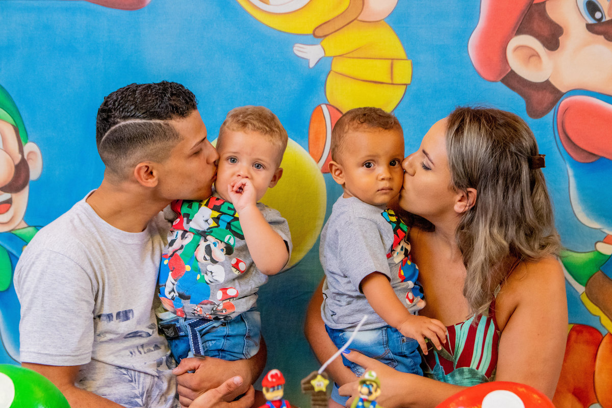 Pais de gêmeos em aniversário, pais beijando os filhos