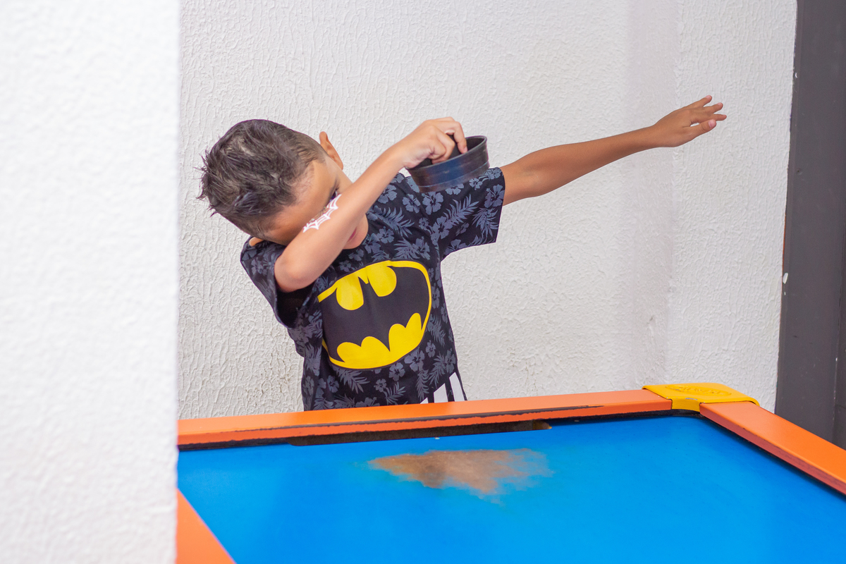 menino vestido de batman comemorando sua jogada no air hockey