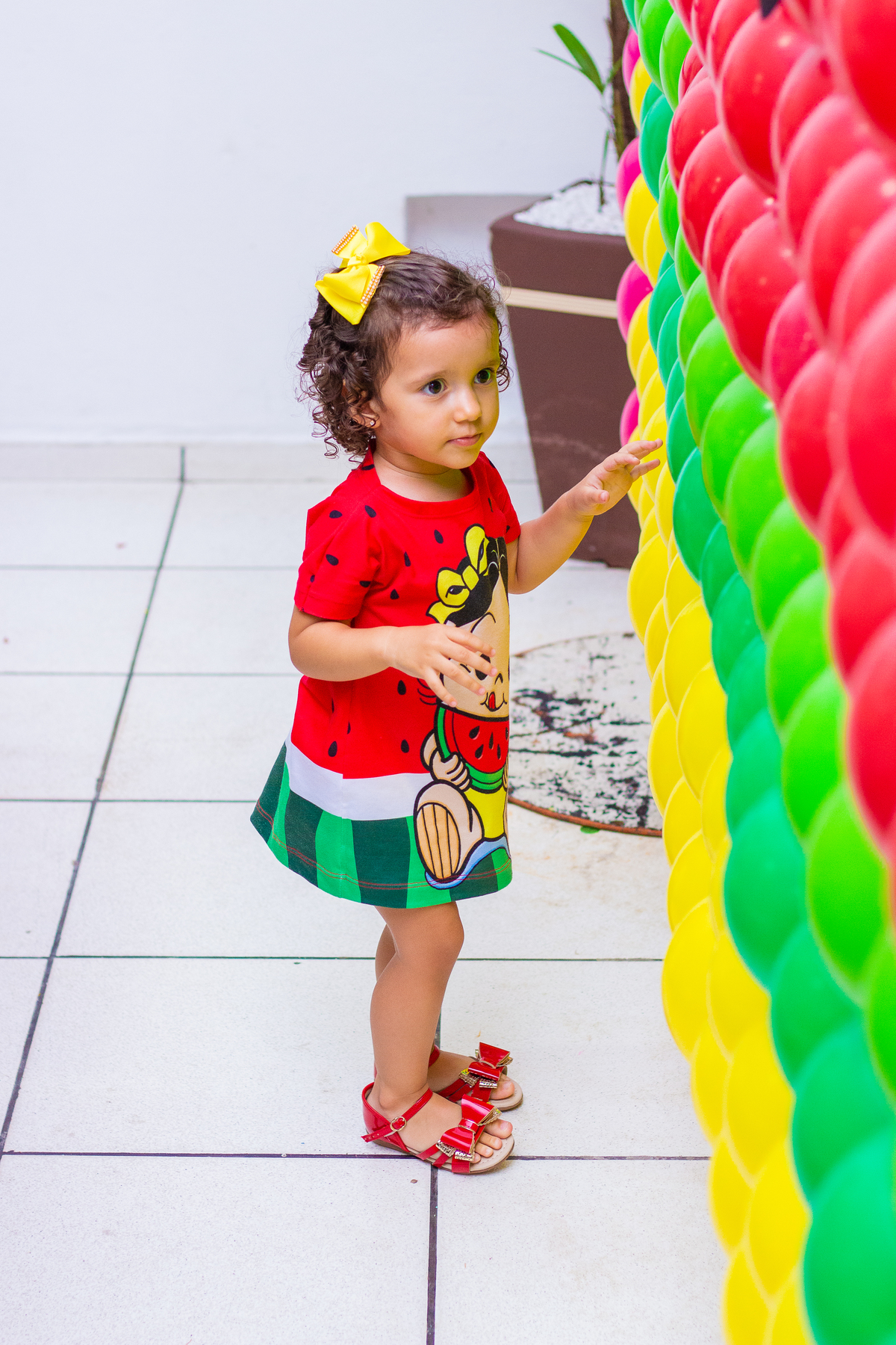 nenê com vestido da magali brincando com os balões do seu aniversário