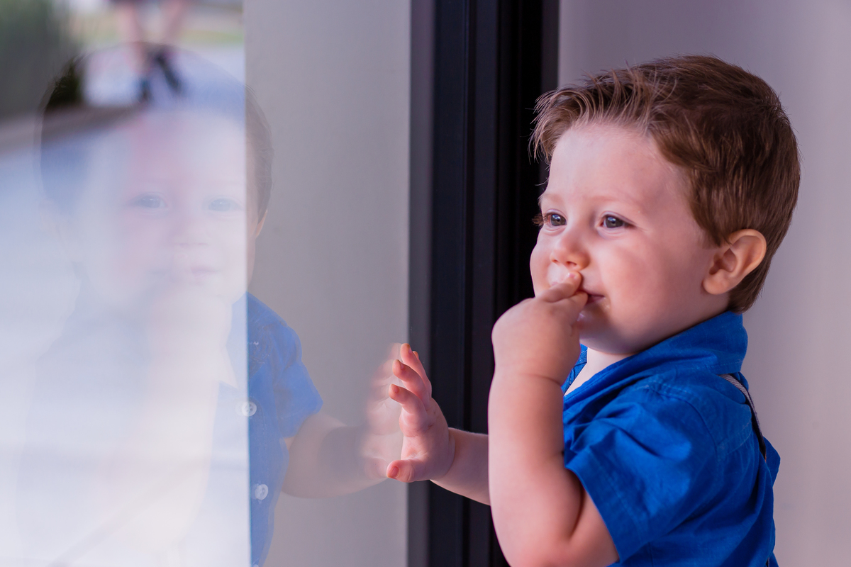 nenê olhando seu reflexo no vidro