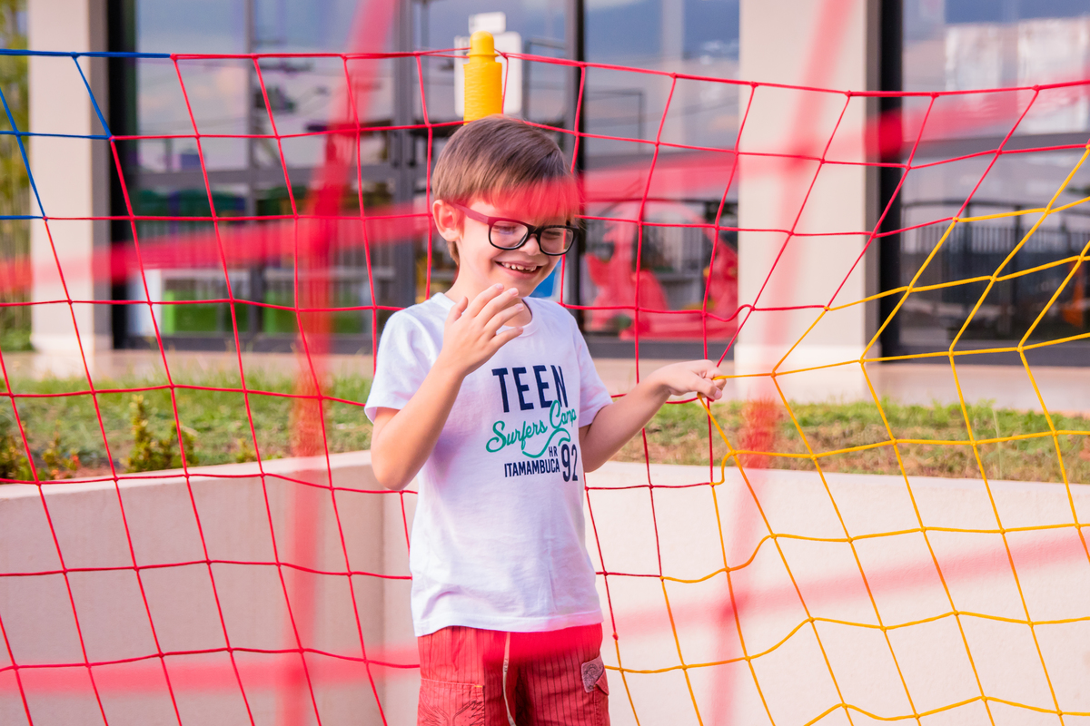 menino de óculos pulando na cama elástica