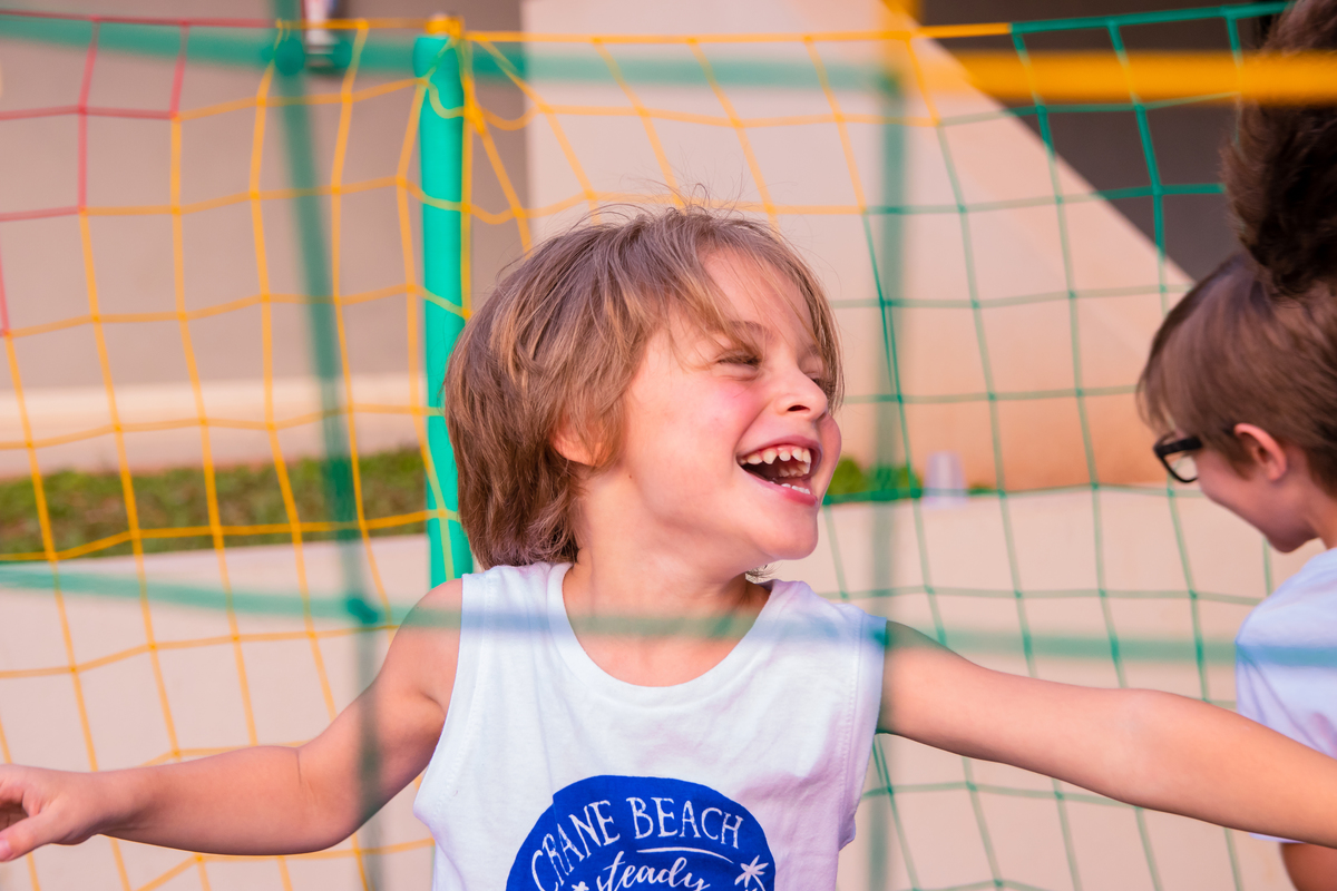 menino loiro sorrindo na cama elástica