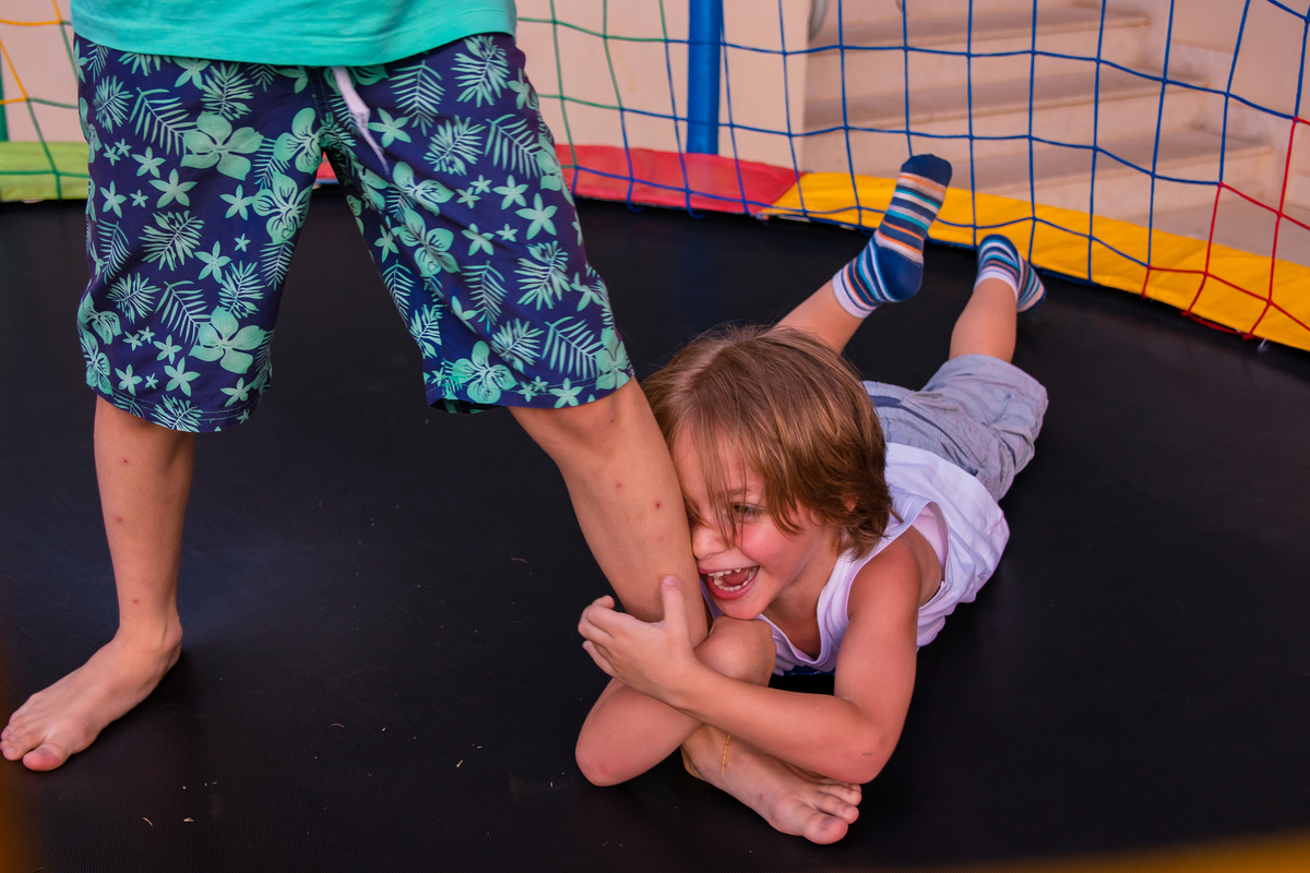 menino agarrando a perna de amigo em cama elástica