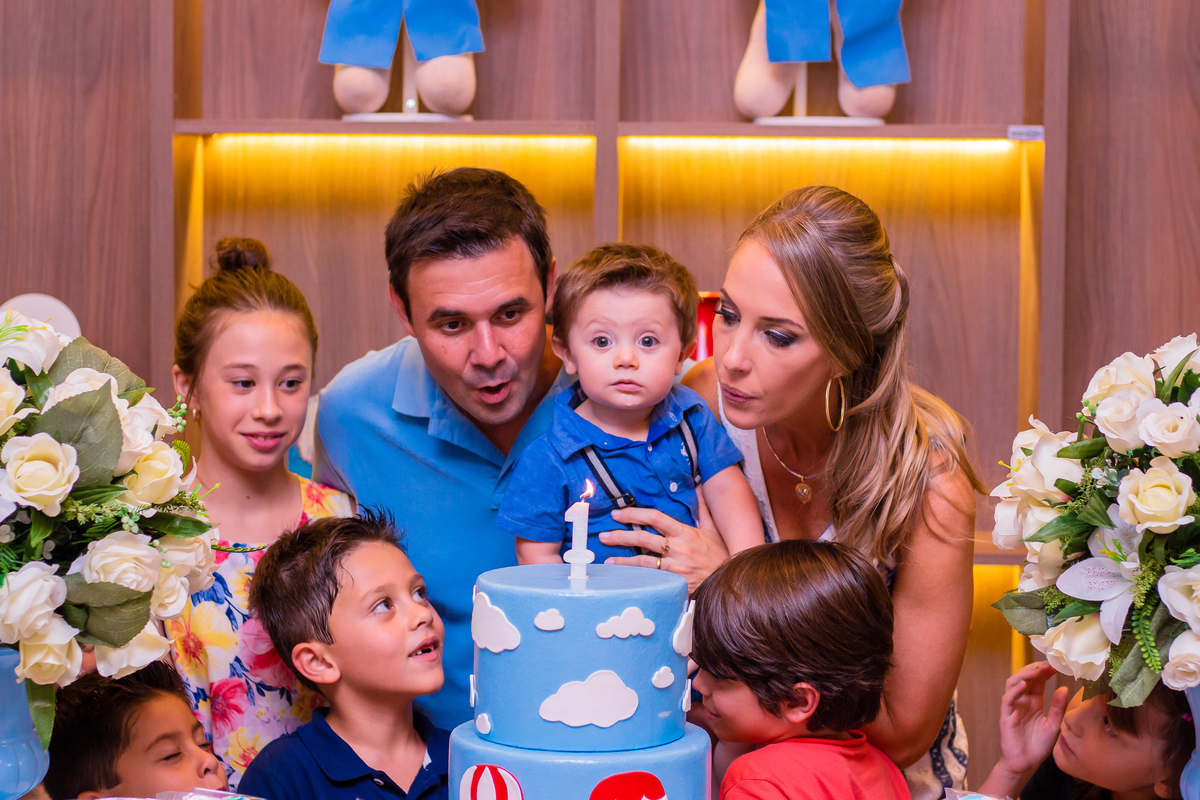 aniversariante e seus pais assoprando as velinhas