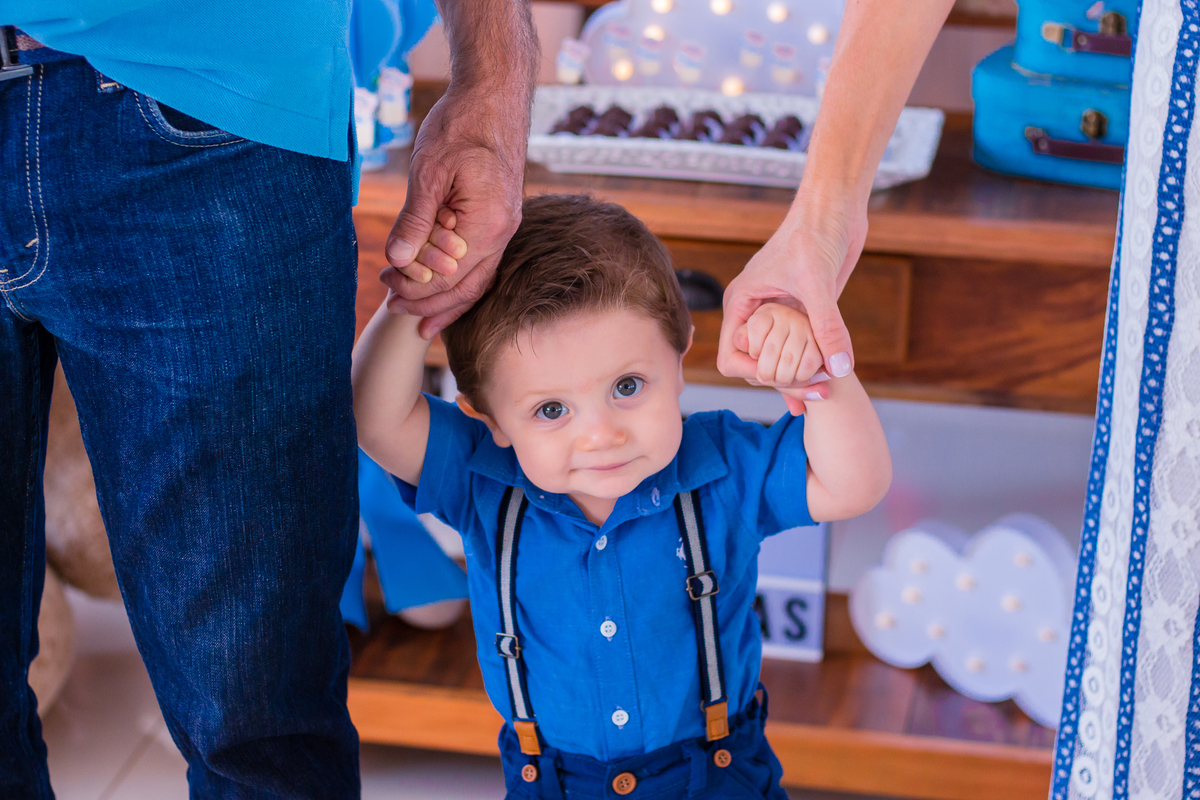 nenê segurando as mãos de seus pais em aniversário