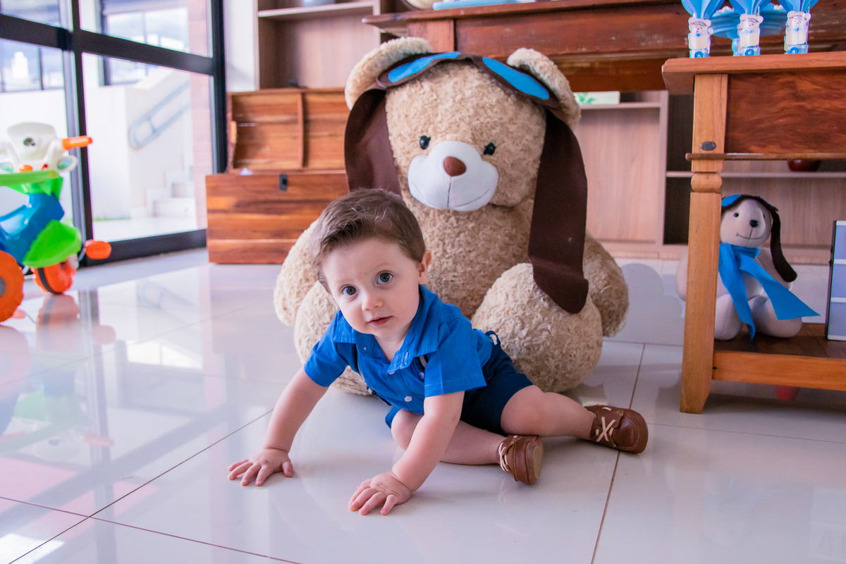 nenê sentado ao lado do urso de pelúcia