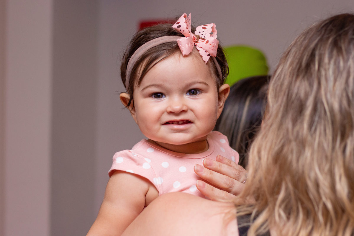 nenê sorrindo para a câmera no colo da tia, laço para nenê