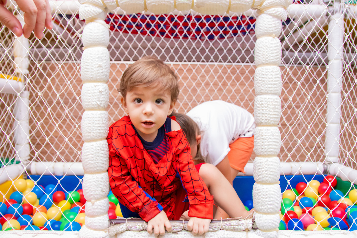 Nenê fantasiado de homem aranha brincando na piscina de bolinhas