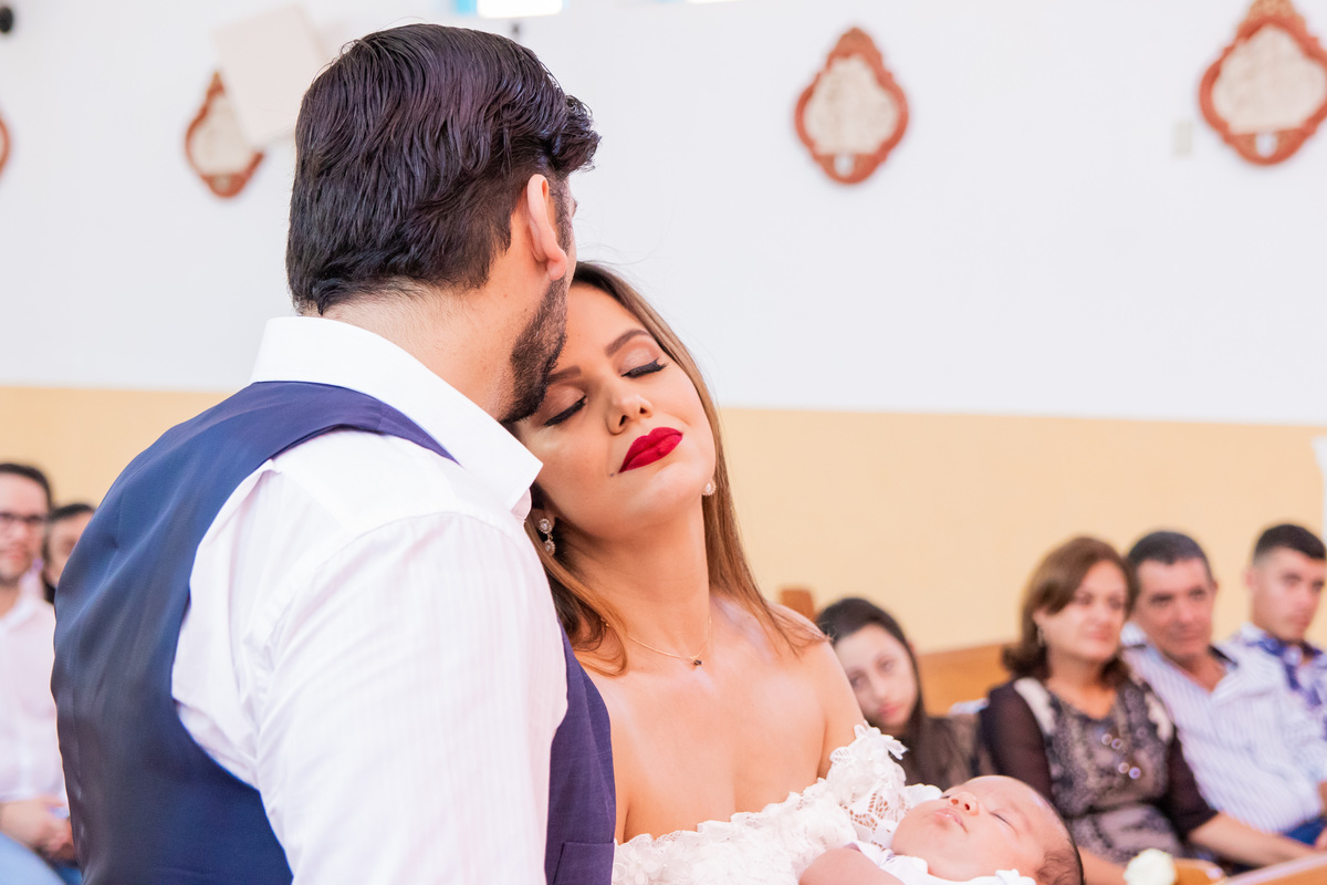 Pais dando um beijo na mãe em batismo