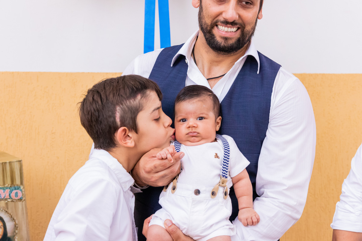 Primo dando beijo no nenê que foi batizado