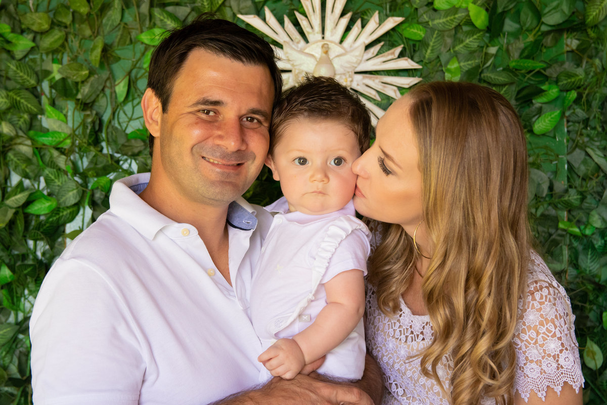 Pais dando beijo no filho que acabou de ser batizado