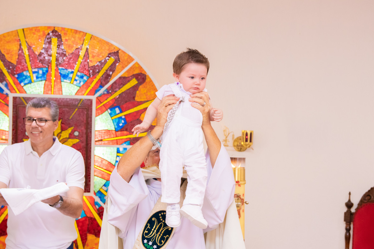 Nenê sendo levantado pelo padre após batismo