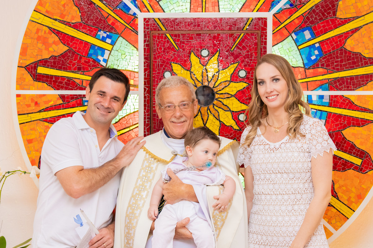 Pai, mãe, filho e padre com o certificado de batismo