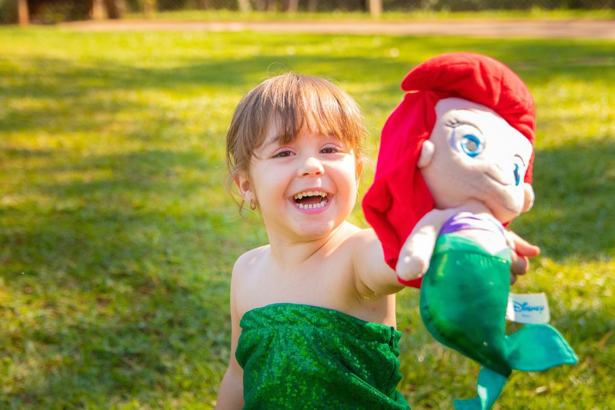ensaio temático a pequena sereia, fantasia pequena sereia, pelúcia da pequena sereia, criança sorrindo no ensaio, jardim botânico bauru