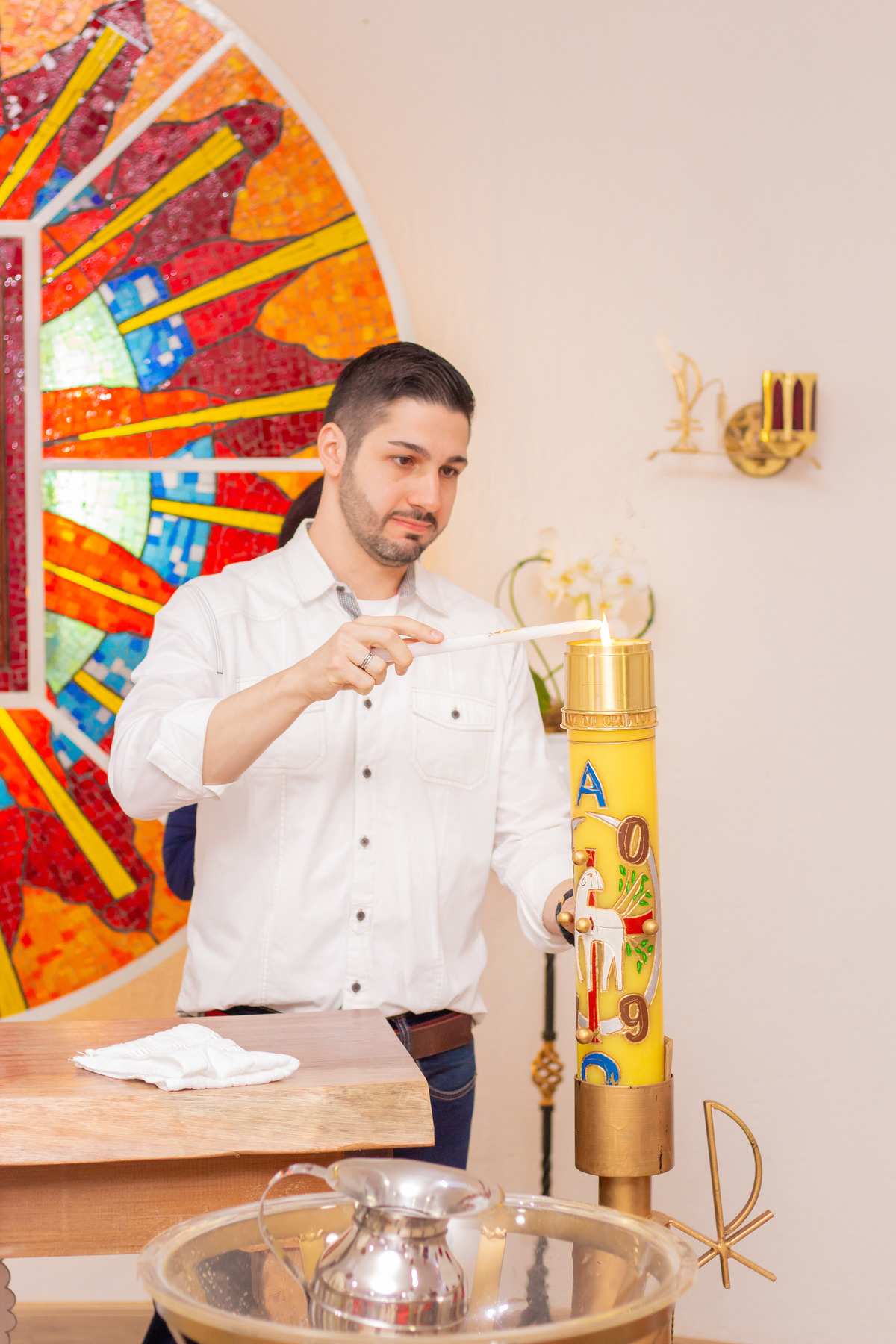 Paróquia Universitária do Sagrado Coração de Jesus - Bauru, padrinho acendendo a vela batismal
