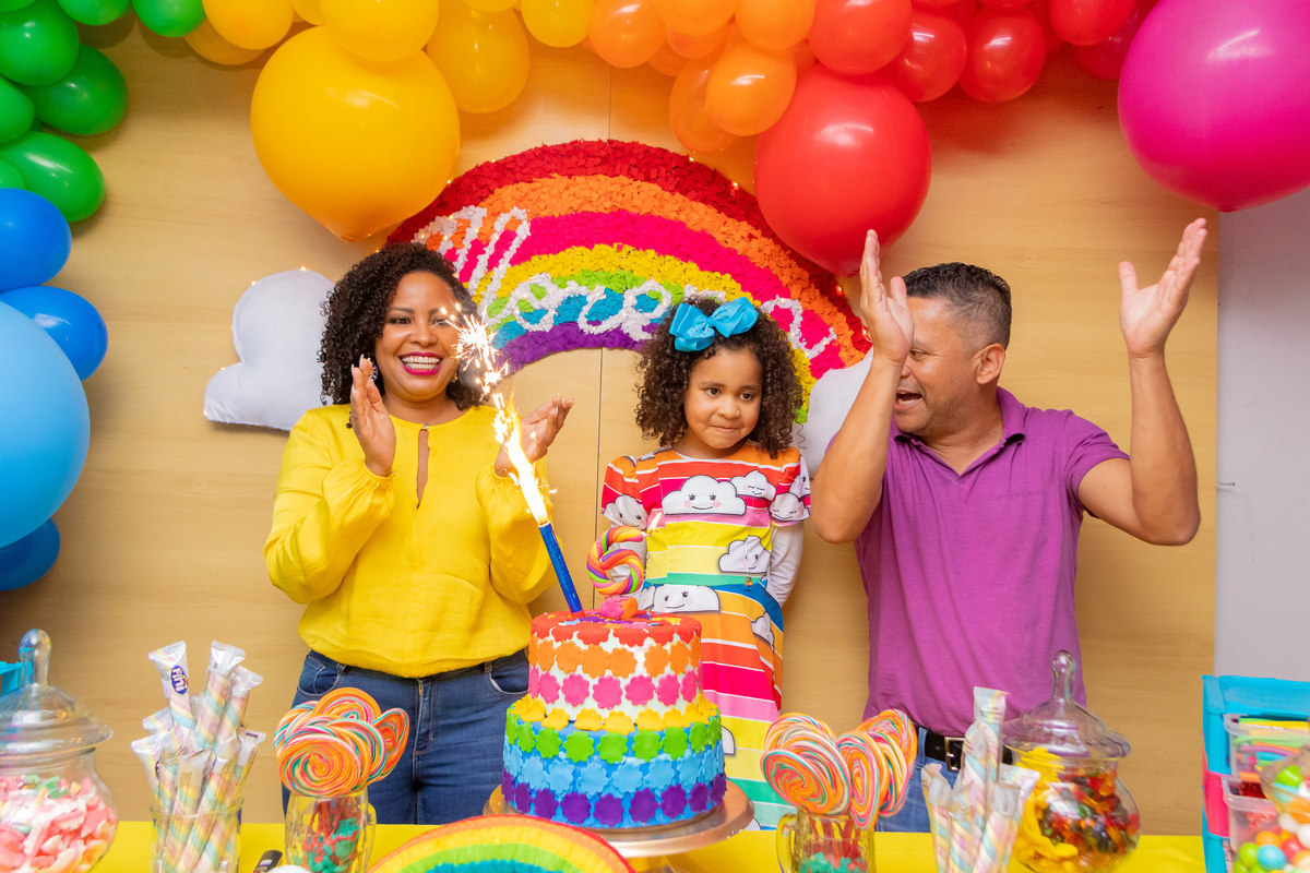 aniversário bauru shopping, decoração fini, decoração arco-iris, família na mesa do bolo cantando parabéns
