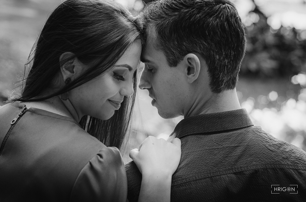 foto em preto e branco. casal sentado de costas para a câmera, testa com testa sorrindo levemente bem apaixonados